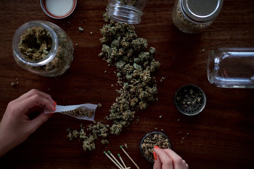 Cannabis, das auf dem Tisch ausgebreitet ist und Hände, die einen Joint drehen